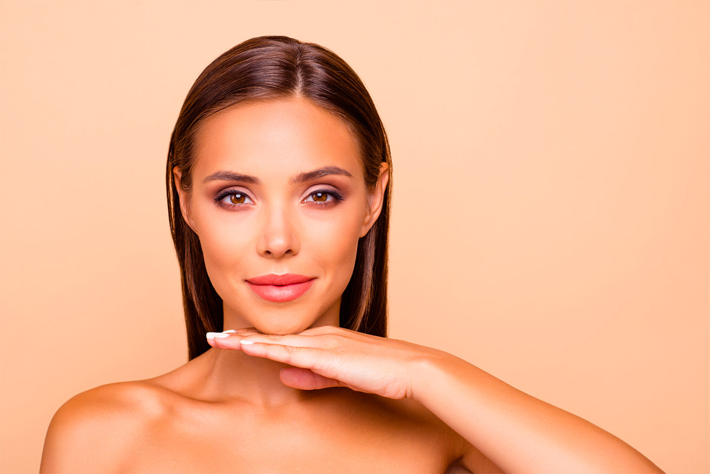 Model lifting her chin peach colored background